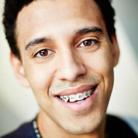 Young man smiling at camera in professional headshot, displaying healthy teeth and orthodontic results.