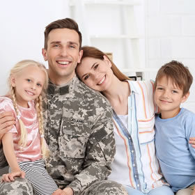 Happy family of four smiling together indoors in bright, clean home setting.